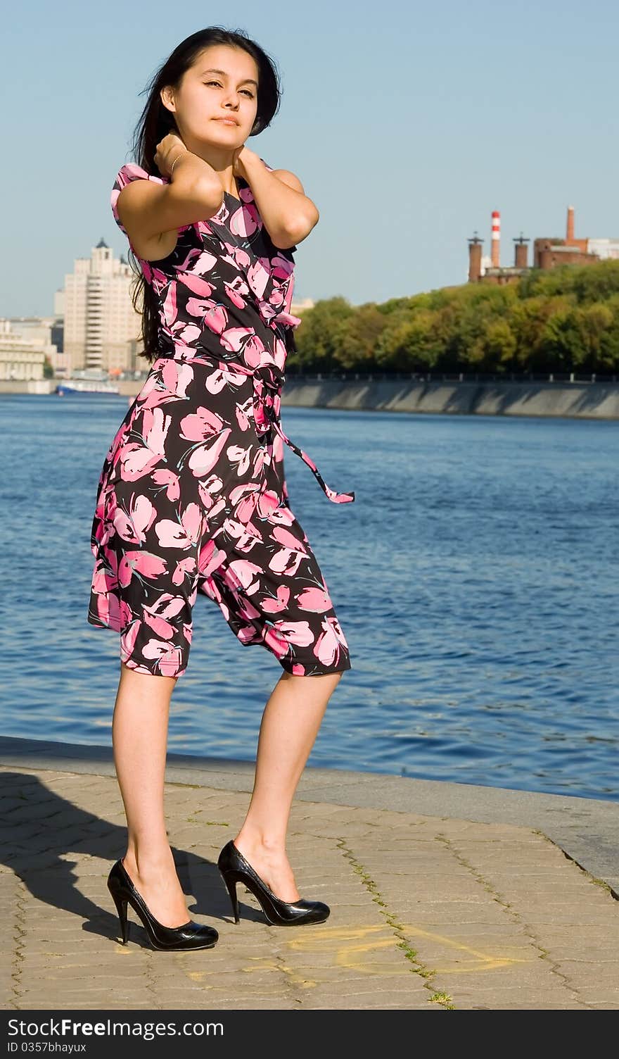 Beautiful Asian girl in a pink dress stands on the banks of the river