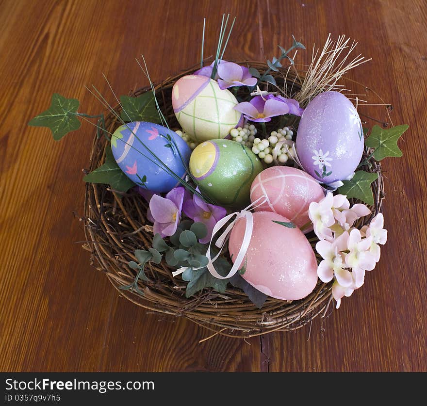 Painted Easter eggs in nest with flowers and overview on a wooden table. Painted Easter eggs in nest with flowers and overview on a wooden table