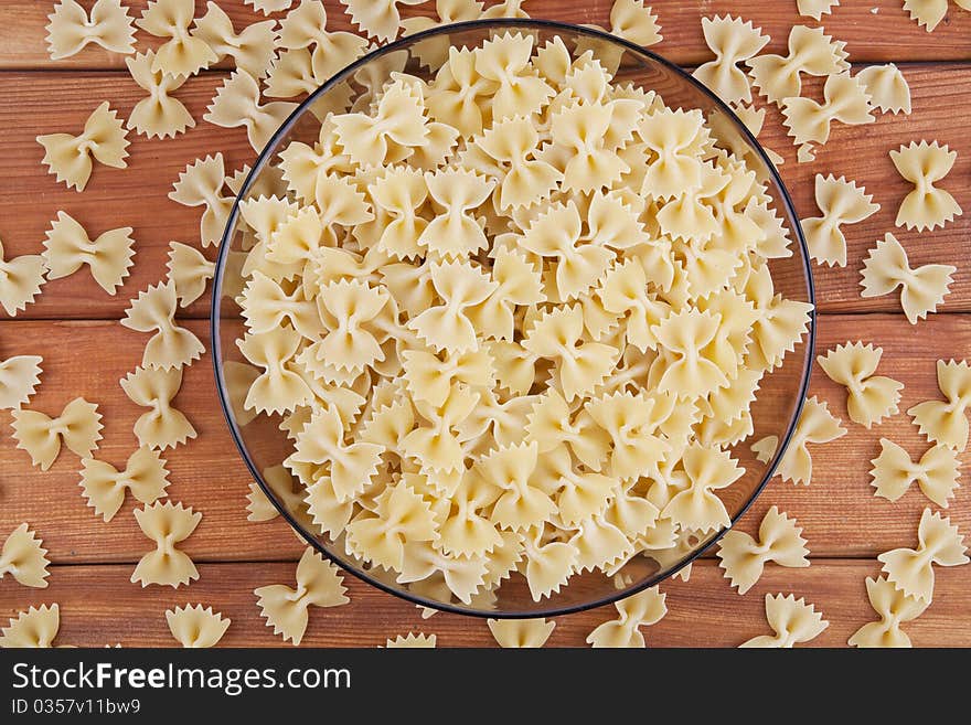 Raw farfalle in glass plate top view. Raw farfalle in glass plate top view