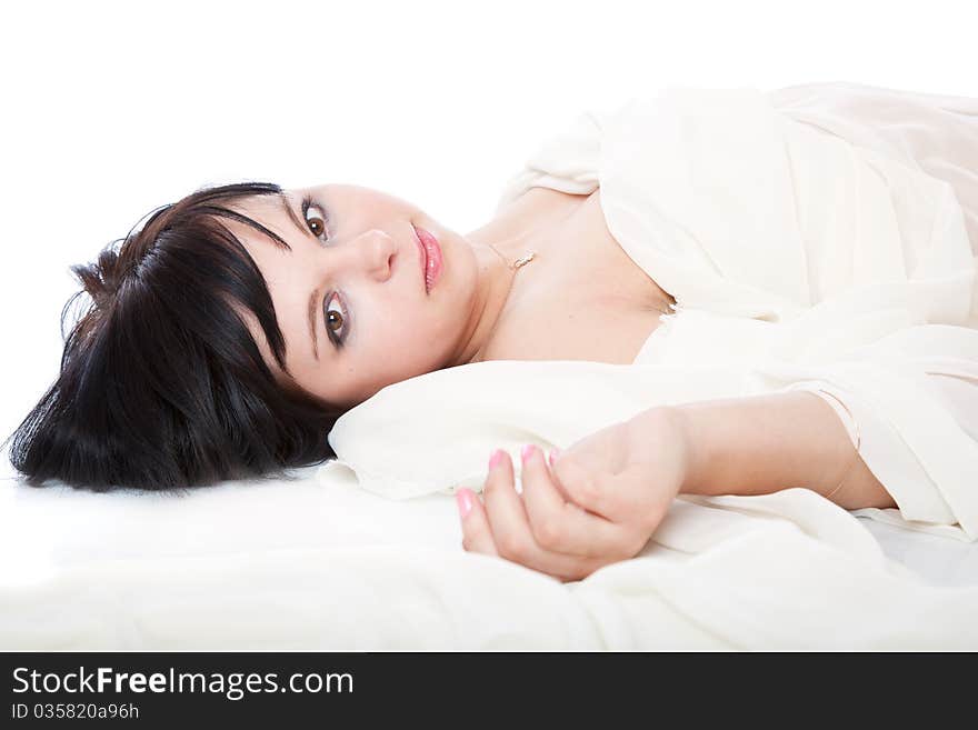 A beautiful young woman is laying on white sheet