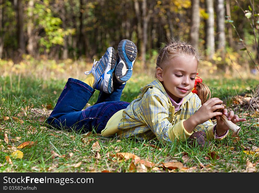 A smiling girl is laying on a grass in the forest. A smiling girl is laying on a grass in the forest