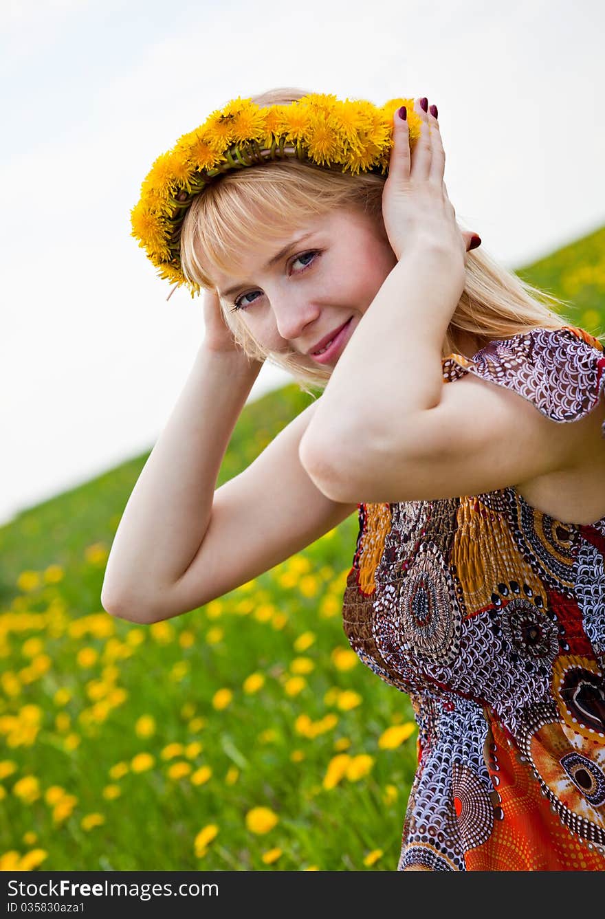 A smiling woman is sitting on a field. A smiling woman is sitting on a field