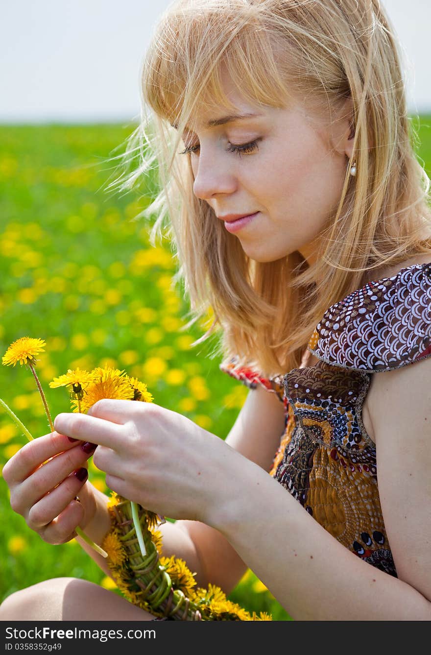 A smiling woman is sitting on a field. A smiling woman is sitting on a field