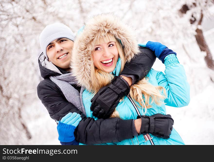 Happy young beautiful couple having a walk in winter park (focus on the man). Happy young beautiful couple having a walk in winter park (focus on the man)