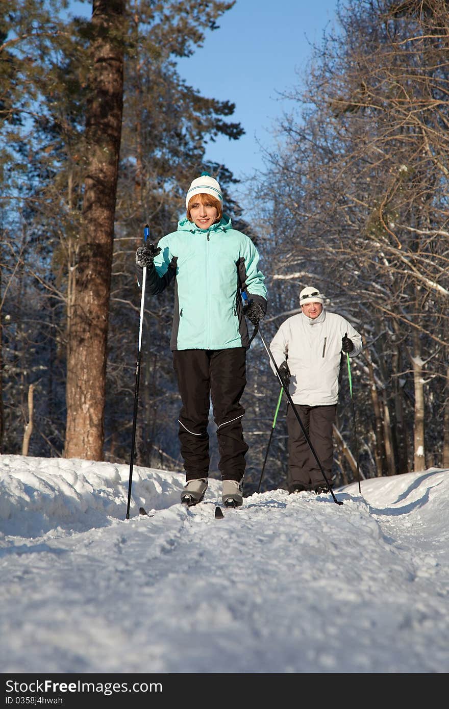 Man And Woman Walk On Ski In Winter Forest