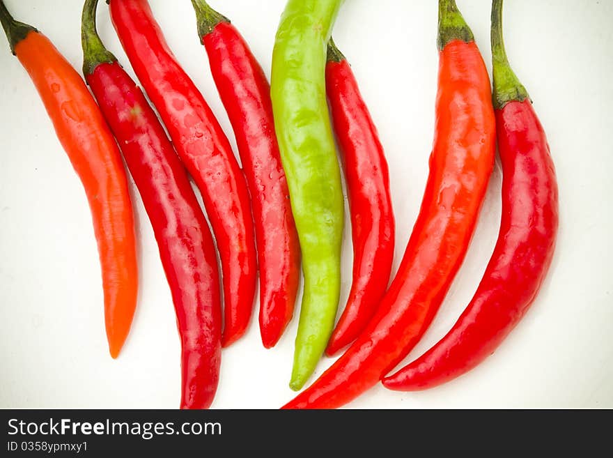 A row of red and green spicy chili peppers on white background