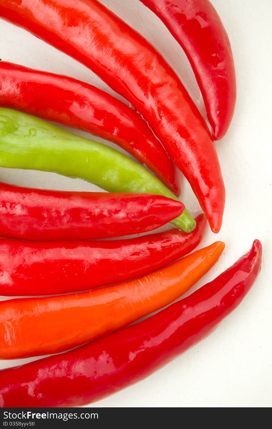 A colorful row of red and green spicy chili peppers on white background