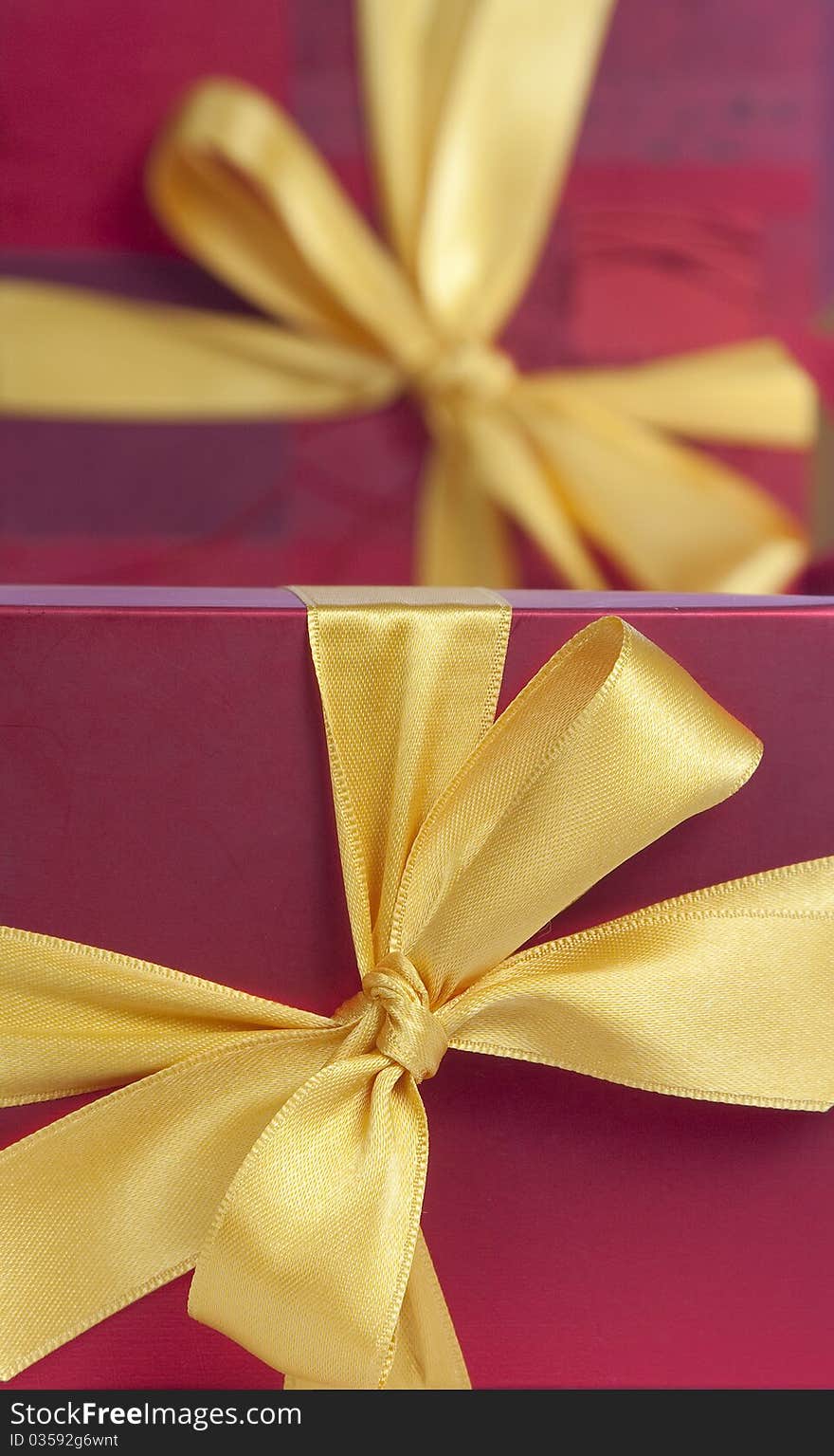 Red gift boxes with yellow ribbons , one blurred behind. Red gift boxes with yellow ribbons , one blurred behind