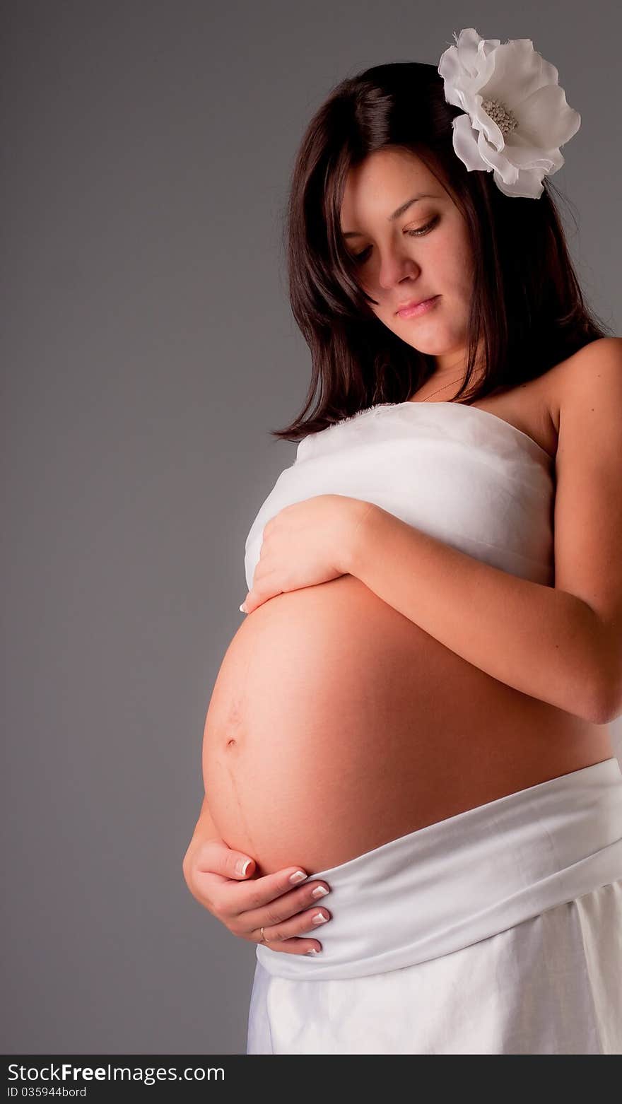 Beautiful pregnant woman staing on grey background, close up