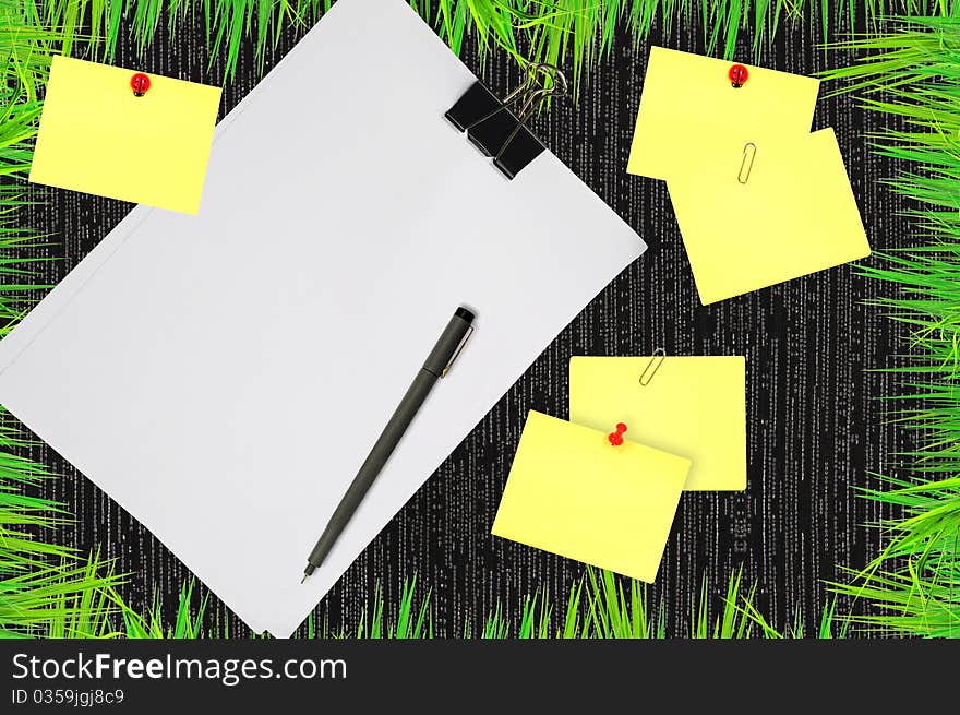 Fresh grass around yellow memo and white blank note paper