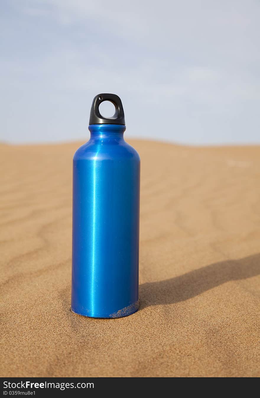 Blue sport water bottle in desert