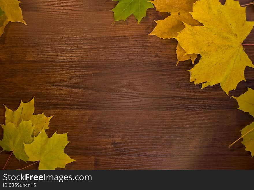 A frame from marple leaves over wooden desk. A frame from marple leaves over wooden desk