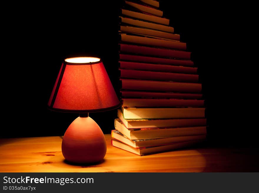 Lamp illuminating books on wooden table