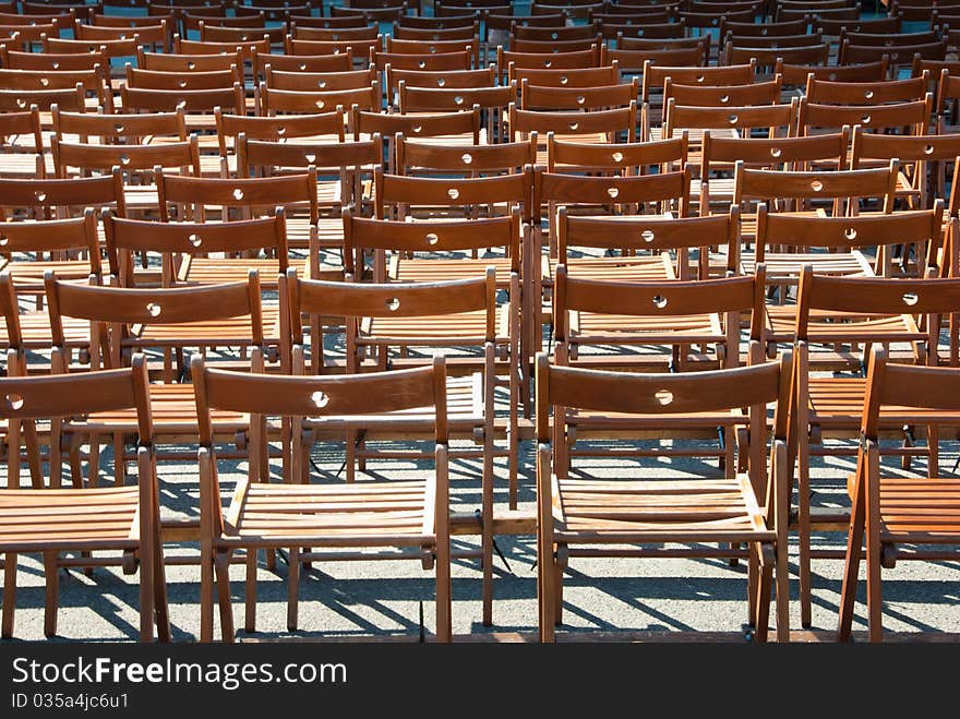 Lots of wooden chairs standing in a row.