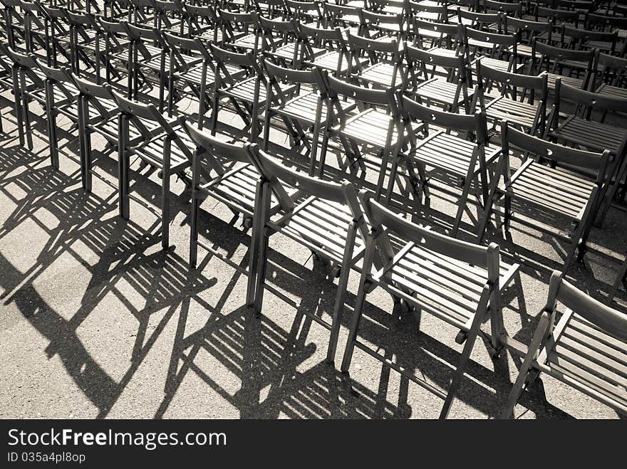 Lots of wooden chairs standing in a row. Monochrome image.