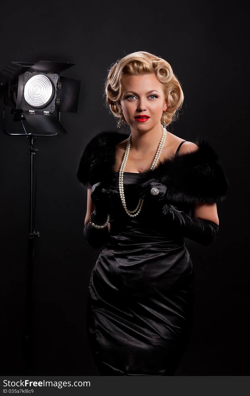 Young blonde woman with fur and necklace on a black background. Young blonde woman with fur and necklace on a black background