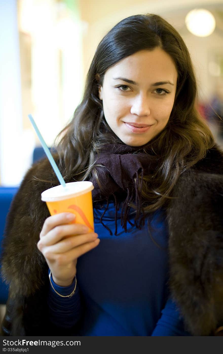 Young girl in fur coat holding a glass of juice