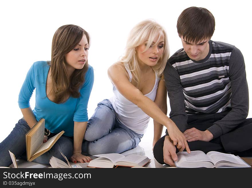 Two beautiful girl and guy thoughtfully reading a book, surrounded by books. Two beautiful girl and guy thoughtfully reading a book, surrounded by books