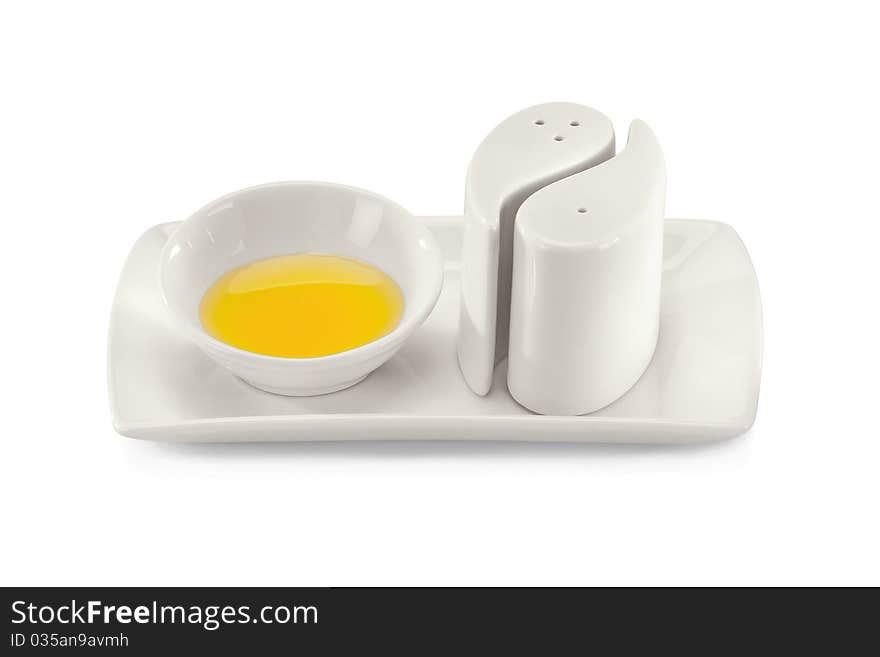 Yellow sauce in a bowl with black pepper pots isolated on a white background.