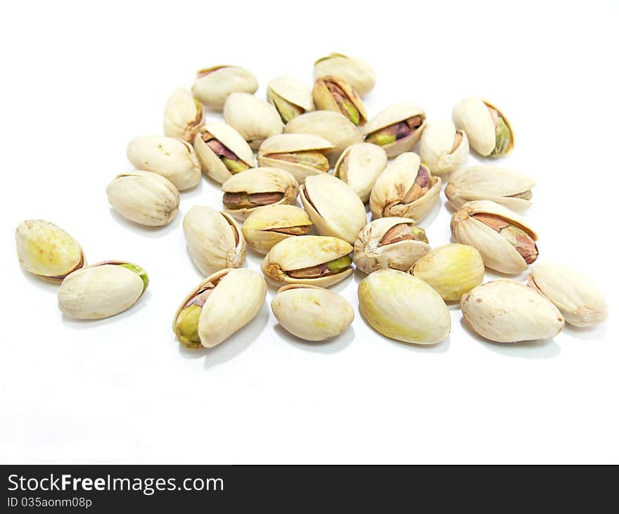 A heap of pistachio nuts scattered on a white background.