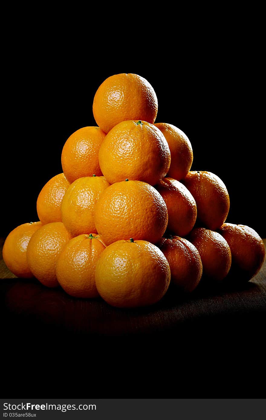 Oranges on wooden table, against black background