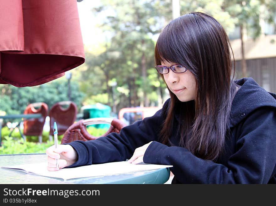 A Chinese girl who is a student, reading books on campus. She is studying hard for exam. A Chinese girl who is a student, reading books on campus. She is studying hard for exam.