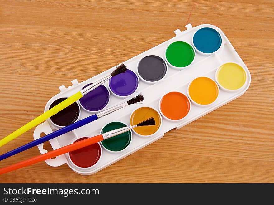 Painters palette with brush on wooden texture