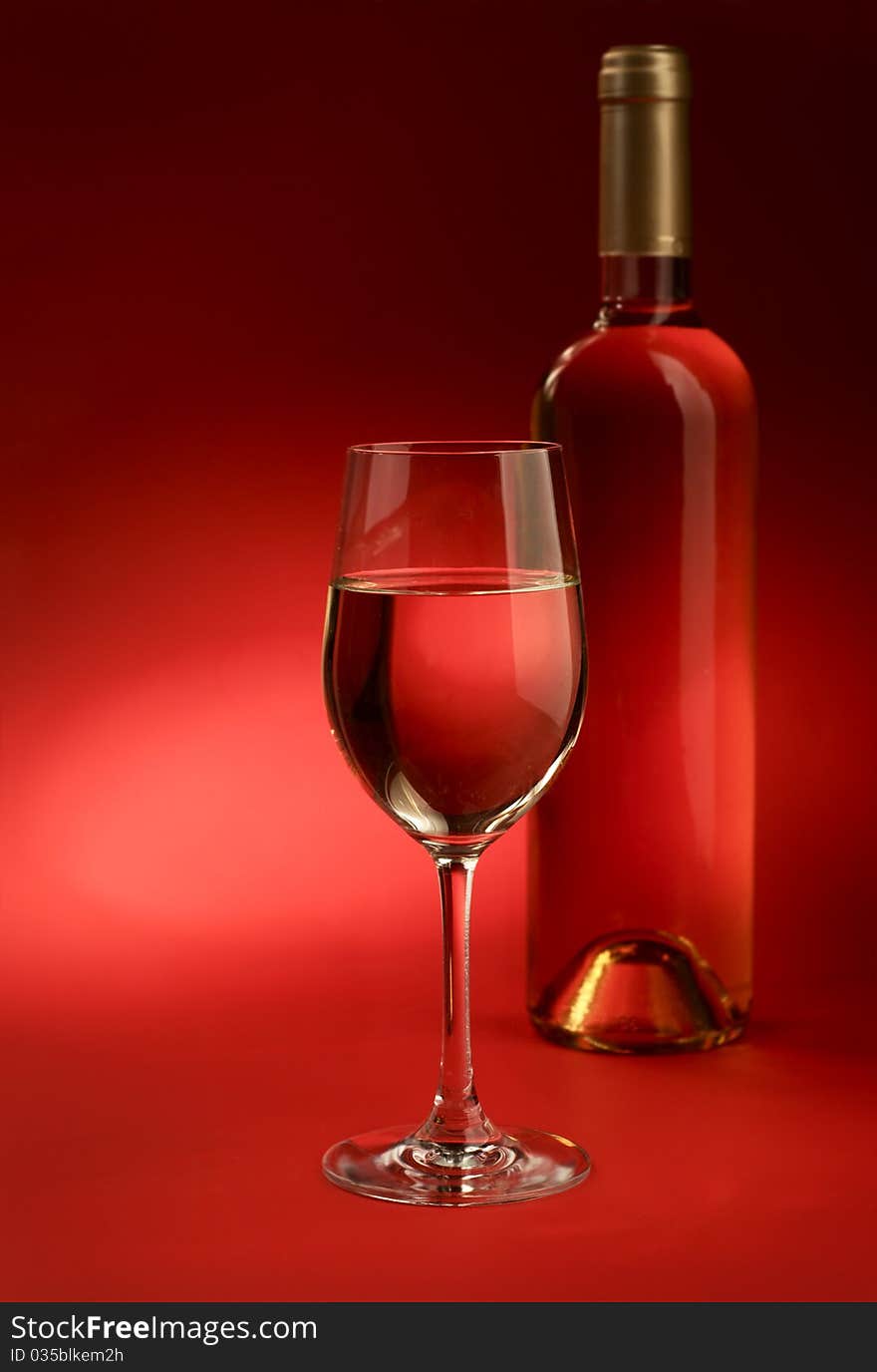 Bottle and glass of wine on a red background. Bottle and glass of wine on a red background