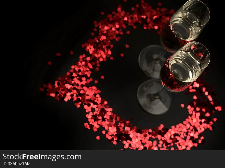 Color confetti and glass of wine on a black background