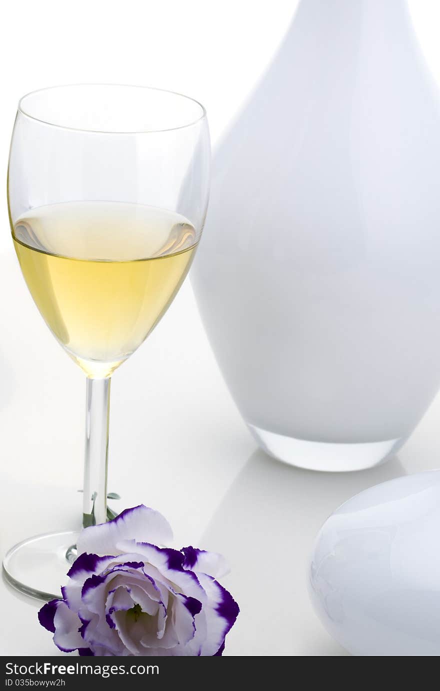 Glass of white wine with flower on white background.