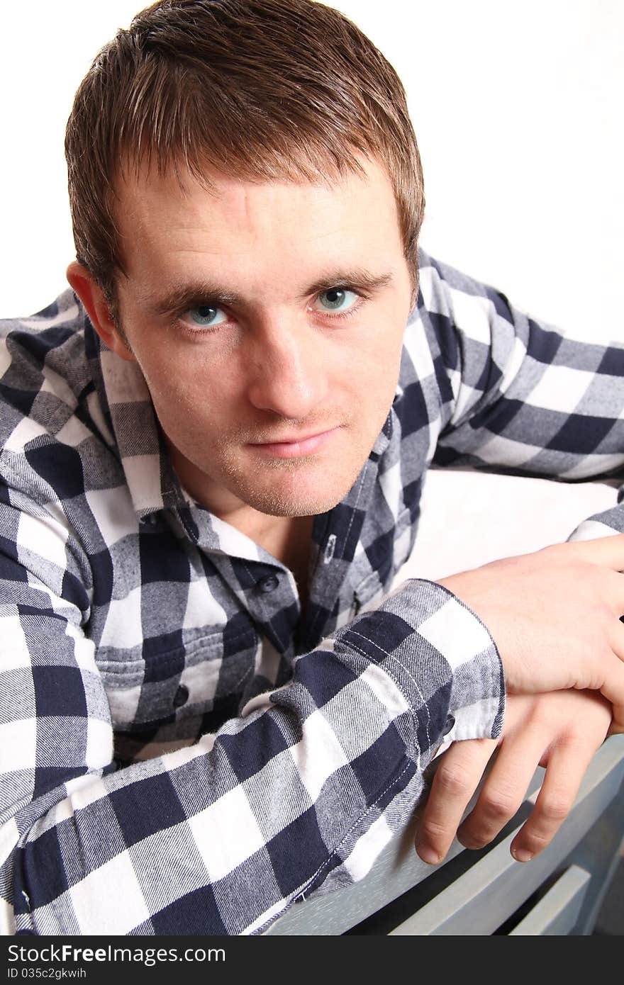 Young male model straddles the chair looking up at the camera. Young male model straddles the chair looking up at the camera