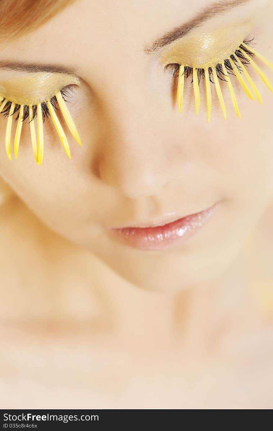 Beautiful young woman wearing yellow petal eyelashes. Beautiful young woman wearing yellow petal eyelashes