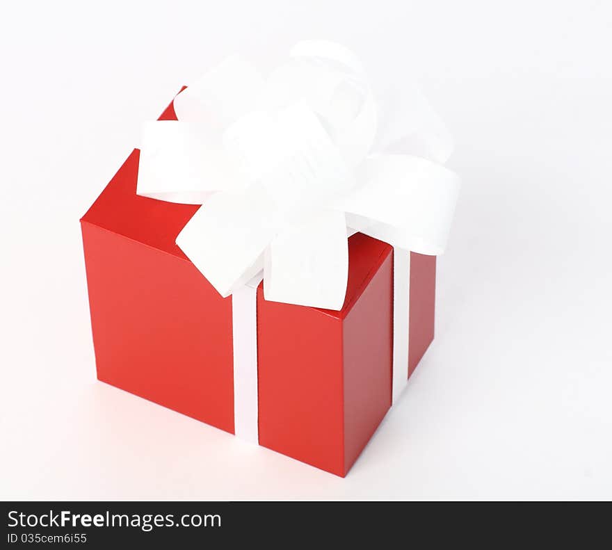 Close-up of a red gift box with white bow on neutral background