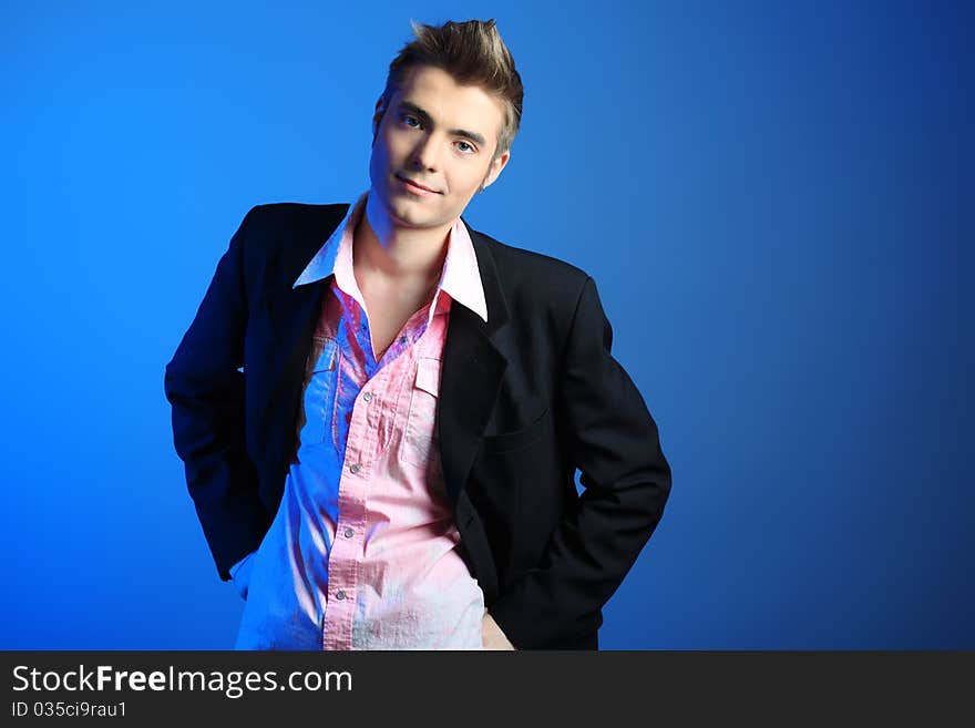 Young man dressed in rock'n'roll style, posing over blue background. Young man dressed in rock'n'roll style, posing over blue background.