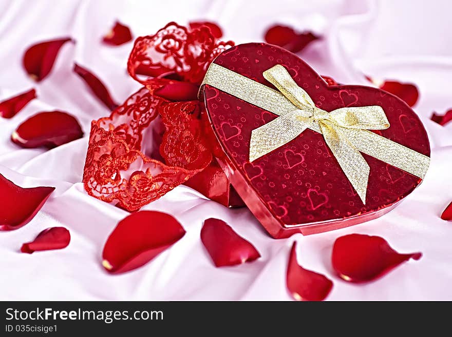 On a pink background gift box heart in the form of women's underwear, the background scattered rose petals. On a pink background gift box heart in the form of women's underwear, the background scattered rose petals.