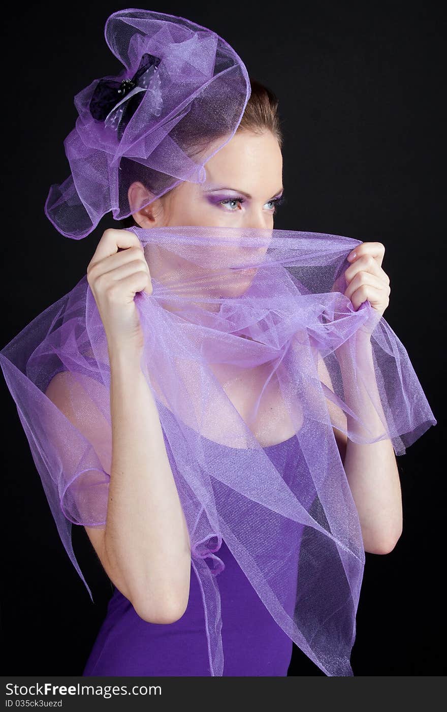 Beautiful young woman with fashionable make-up in a little violet hat isolated on black. Beautiful young woman with fashionable make-up in a little violet hat isolated on black