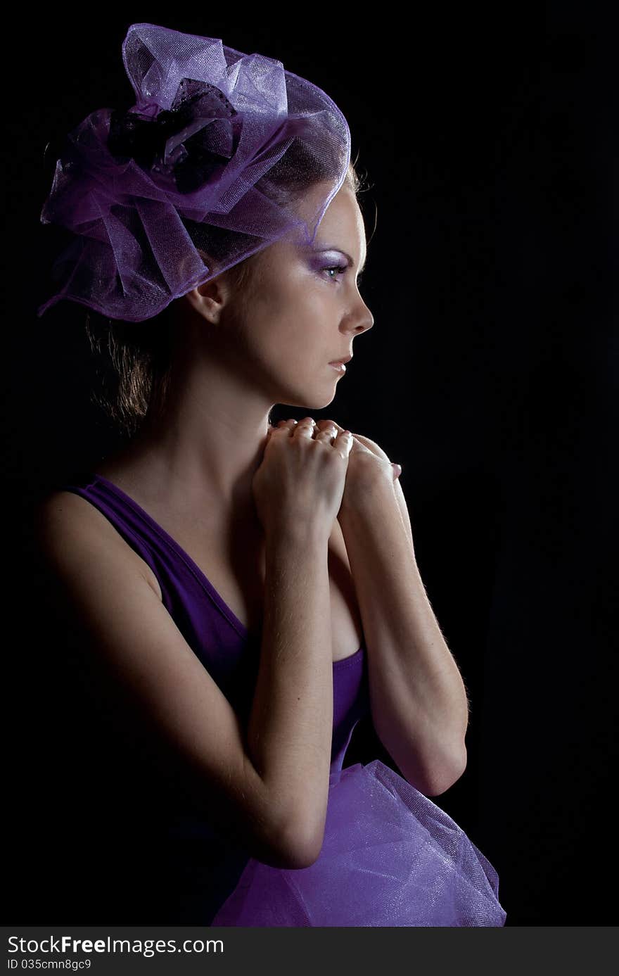 Beautiful young woman with fashionable make-up in a little violet hat isolated on black. Beautiful young woman with fashionable make-up in a little violet hat isolated on black