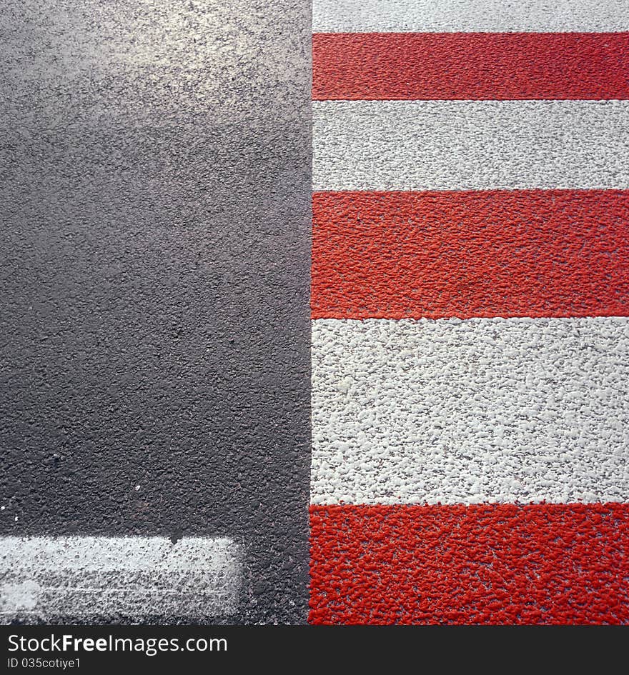 Red - white road marking on a pedestrian crossing.  . Red - white road marking on a pedestrian crossing.