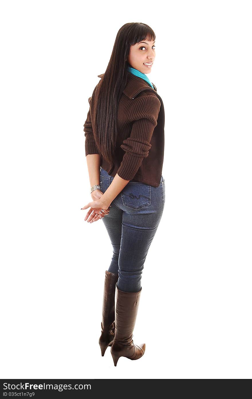 A beautiful woman standing with her back to the camera in jeans and a brown sweater and boots and long black hair, on white background. A beautiful woman standing with her back to the camera in jeans and a brown sweater and boots and long black hair, on white background.