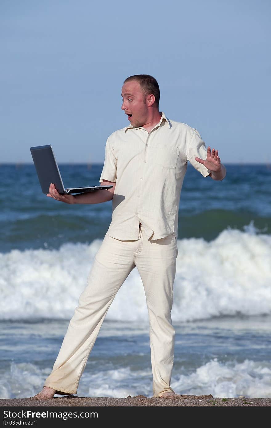 Young businessman at the beach with his laptop happy about success. Young businessman at the beach with his laptop happy about success