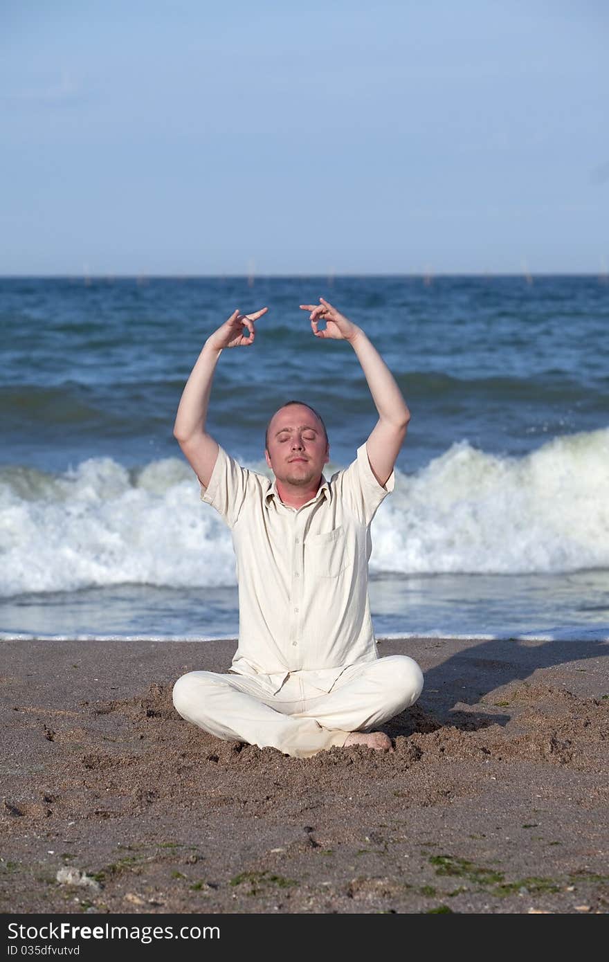 Young businessman doing yoga on a beautiful beach. Young businessman doing yoga on a beautiful beach