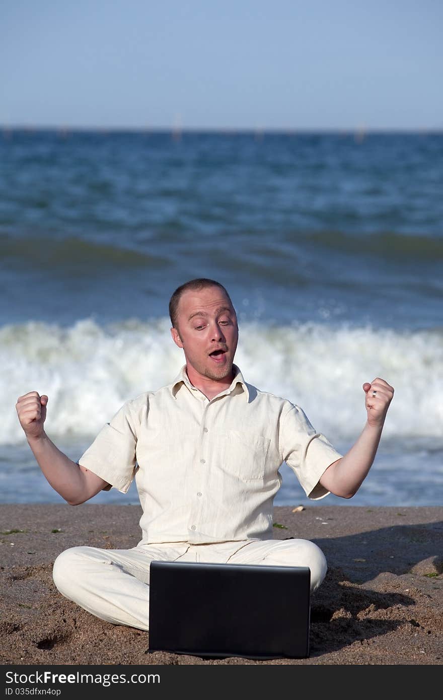 Young businessman at the beach with his laptop happy about success. Young businessman at the beach with his laptop happy about success