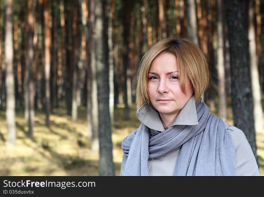 Woman wearing grey coat and scarf on a walk in the forest - portrait. Woman wearing grey coat and scarf on a walk in the forest - portrait.