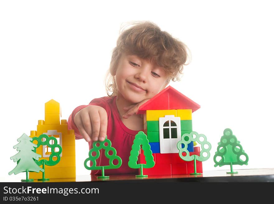 Cute little girl is constructing a house using building blocks