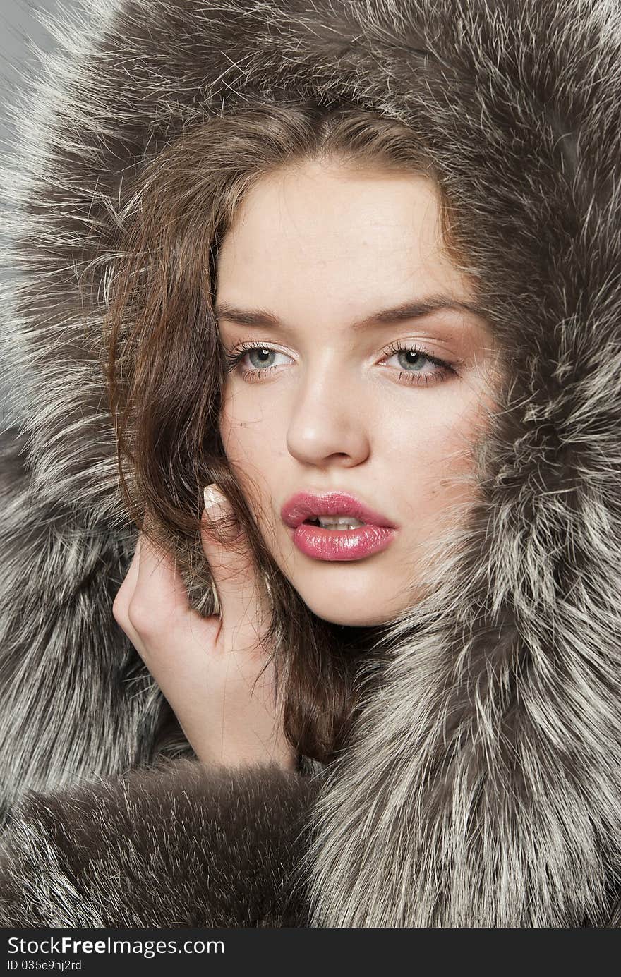 The young beautiful girl with chubby lips in a fur coat. The young beautiful girl with chubby lips in a fur coat