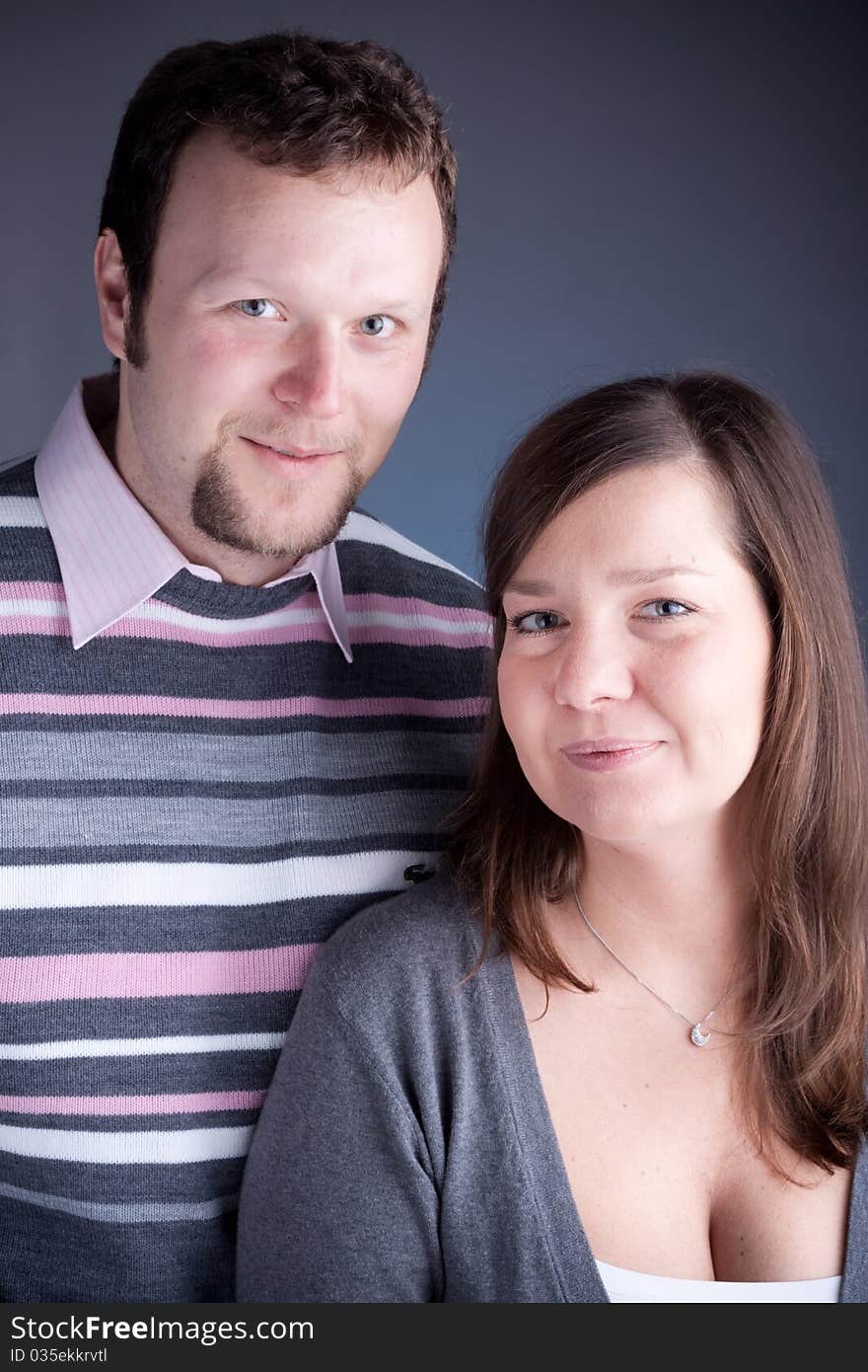 Portrait of a beautiful young couple hugging each other against grey backround