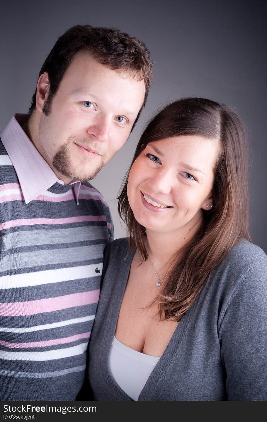 Portrait of a beautiful young couple hugging each other against grey backround