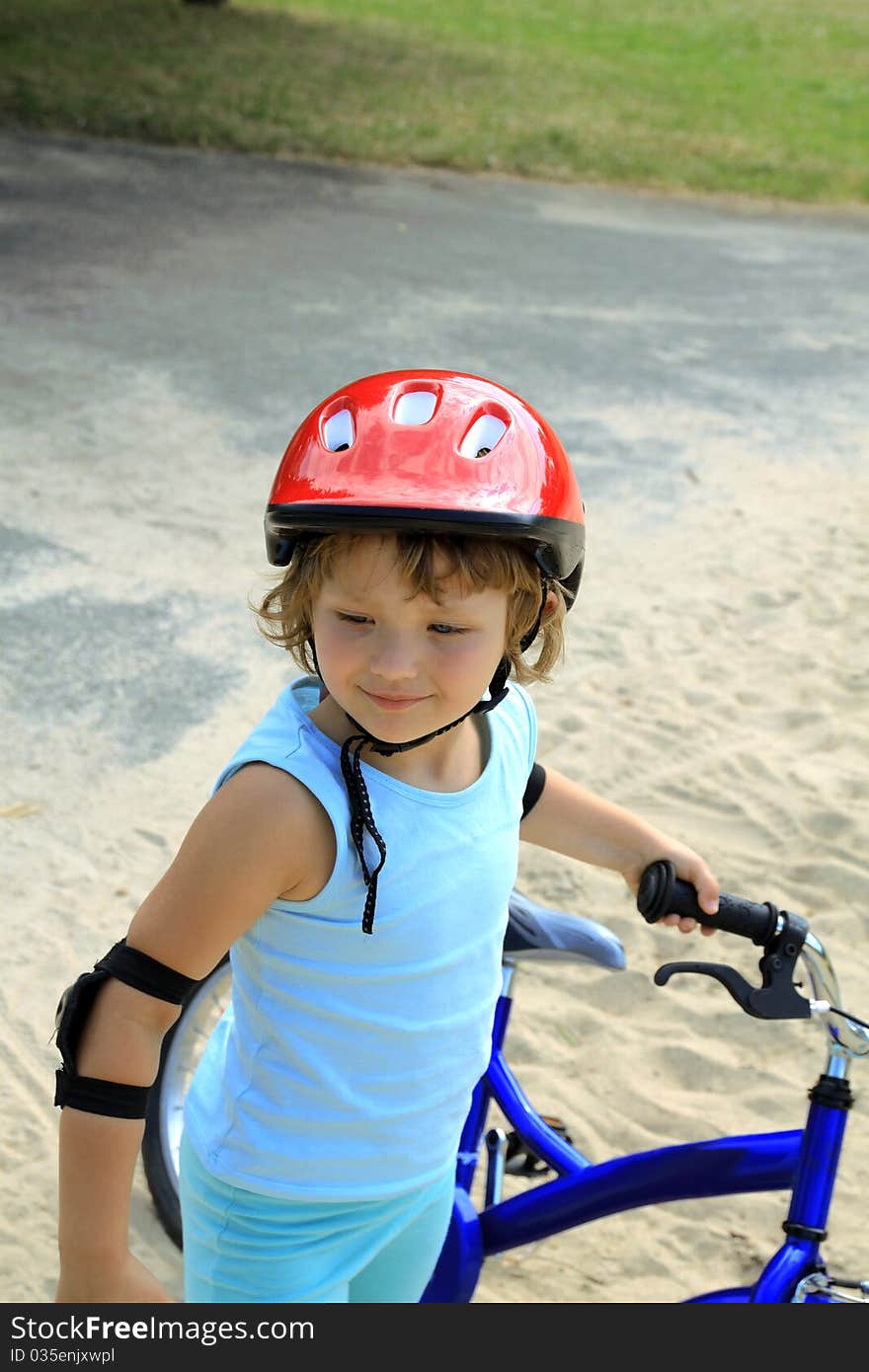 Girl in a red helmet, holding a bicycle. Girl in a red helmet, holding a bicycle