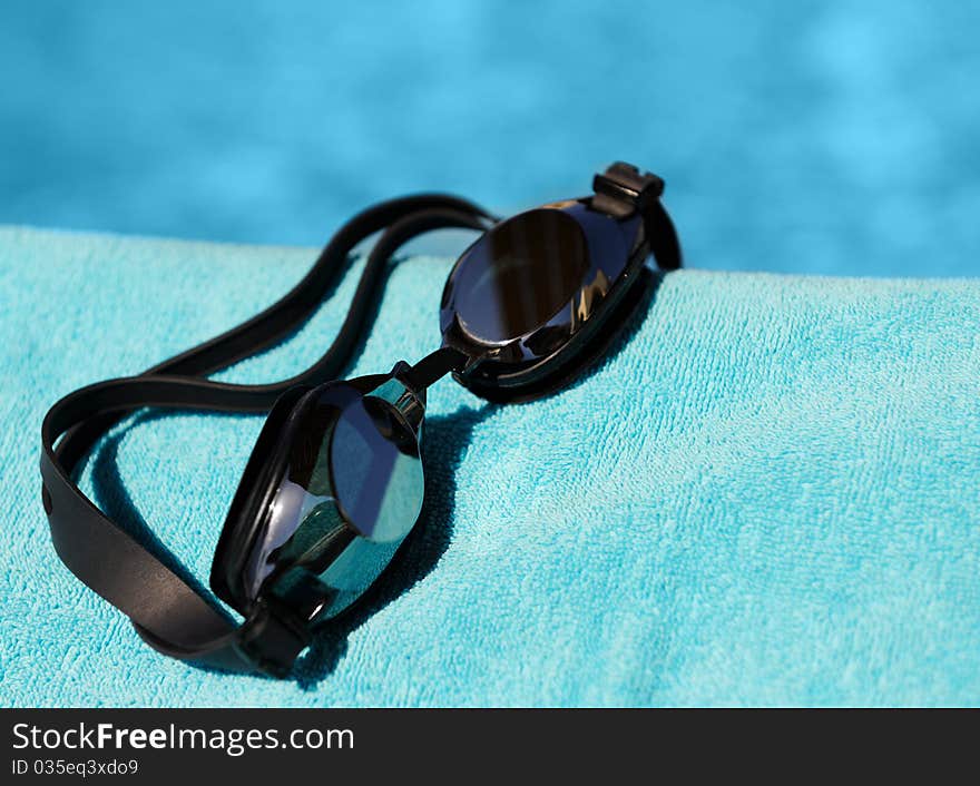 Swimming glasses on a blue towel against water