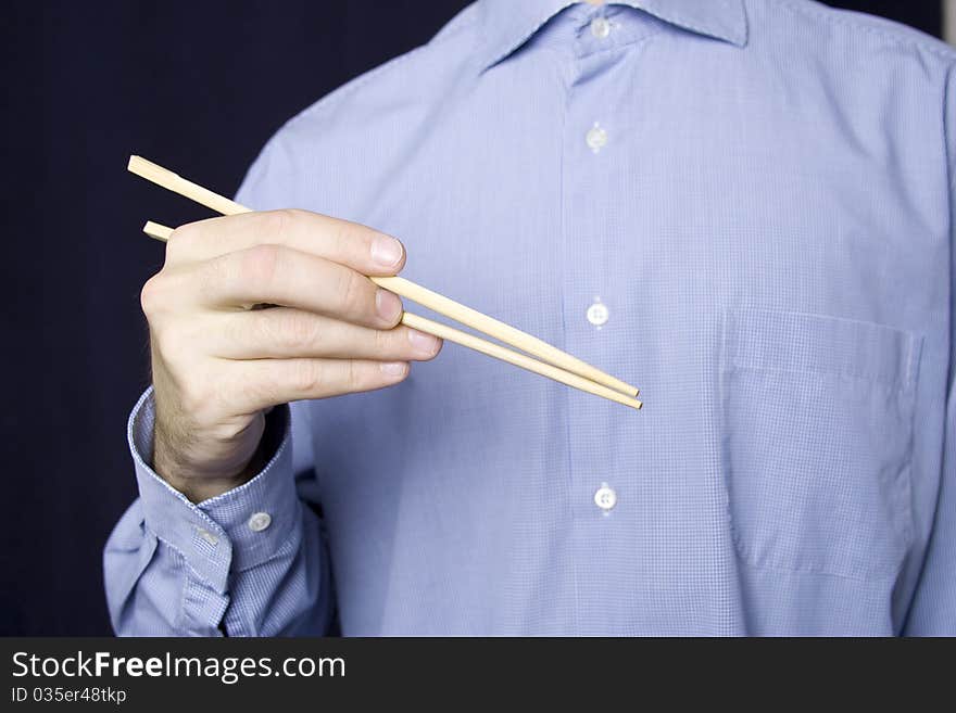 A young man in a blue shirt in his hand, wooden sticks for land. A young man in a blue shirt in his hand, wooden sticks for land